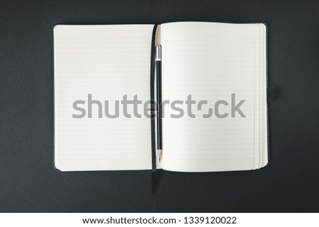 A classic notebook with pencil on a black background