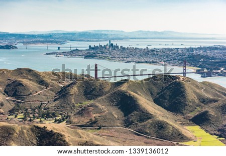 Aerial photograph of San Francisco skyline, Golden Gate Bridge, Marin Headlands, Bay Bridge and East Bay. Shot from a small plane above Rodeo Beach, facing southeast.