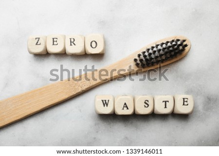 Biodegradable organic bamboo toothbrush and  inscription from the cubes "zero waste" on marble background. Top view, Concept ecology.