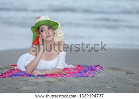 thai girl tourists in white dress  sleeping relaxation and posting pictures happily on the beach at the sea rayong on weekend Thailand