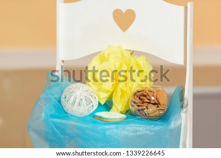 Photo zone on the street. Girl's birthday. Cookies in a glass jar. White chair. Blue fabric on the chair. Decorative flowers made of paper.
