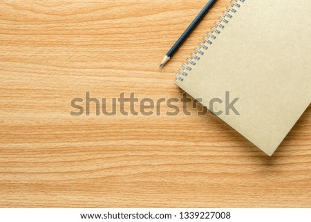 book and a pencil on wooden desk. - for creative and business concept background.
