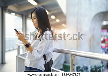 Traveler asian woman touching smartphone and using social network for planning her route for travel, waiting someone stay at overpass.                               