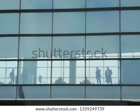 Airport passenger terminal waiting area. Groups of Passenger waiting time for boarding in the airplane. Seen from outside the terminal in silhouette.