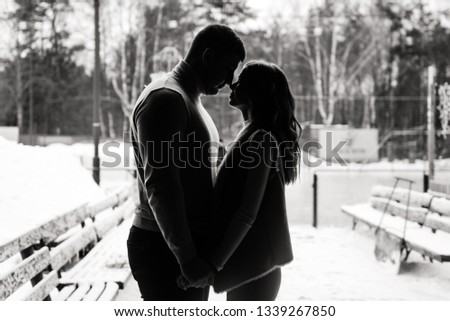 Winter love story on ice. Silhouettes of a guy and a girl. Black and white photo