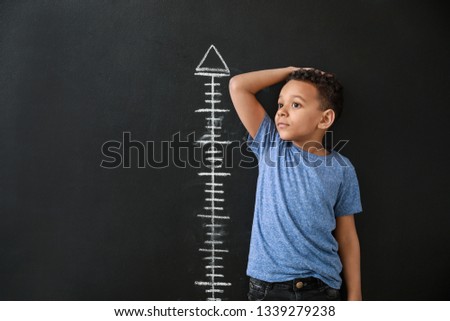 African-American boy measuring height near dark wall