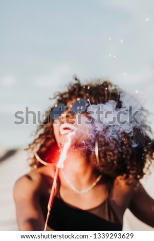 Young afro woman with sparklers and sunglasses