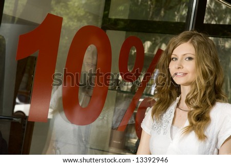 Pretty woman standing near shop window with 10% discount sign