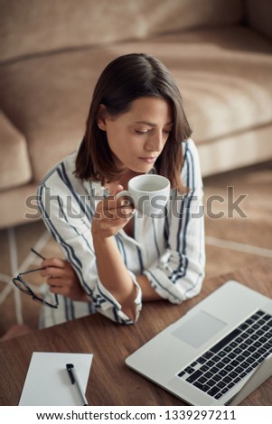 young woman relaxing at home with laptop computer and drinking coffee
