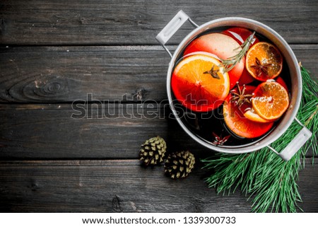 Mulled wine with fir branches. On a wooden background.