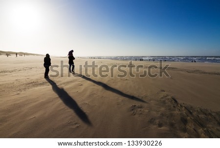 Silhouette family with long shadows on the beach on a stormy winter day