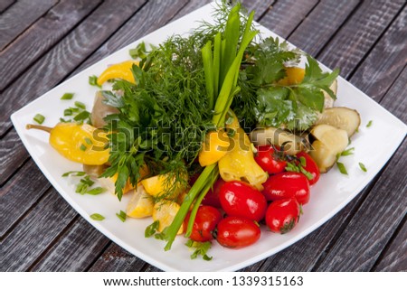 
juicy, summer vegetable salad cutting from fresh vegetables and greens in a beautiful serving on a wooden table for decoration and design