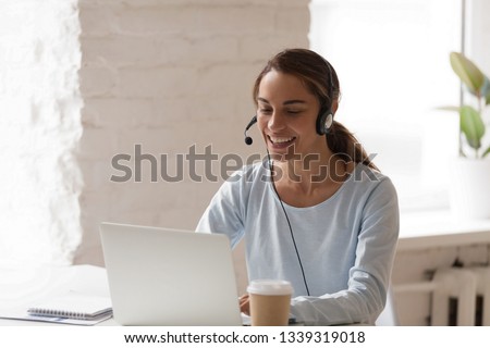 Beautiful smiling woman working in headphones at office. Call center introduction. Happy employee at workplace. People at work at home. Video job interview, language course, class concept Royalty-Free Stock Photo #1339319018