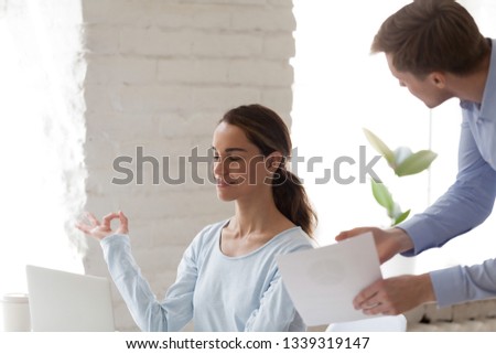 Office female keep calm when angry boss shout. Beautiful girl meditating at desk in stress situation with eyes closed. Feel harmony, relax, meditation, yoga, healthy habits, stress free image concept