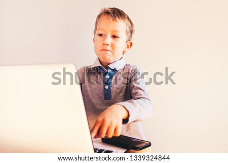 Child working with his computer in his business, concentrated typing to succeed, funny image.