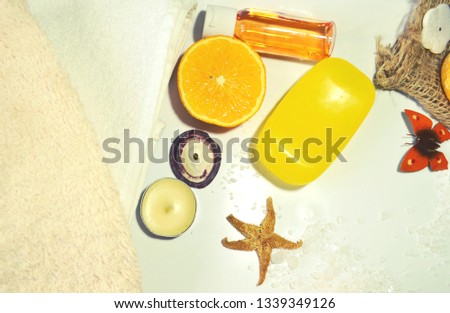 Spa composition of organic orange skin and hair care products of tonic and vitaminizing action with soap, citrus shampoo, cotton towels, candles, orange slice. Summer spirit. Mood-enhancing treatment.