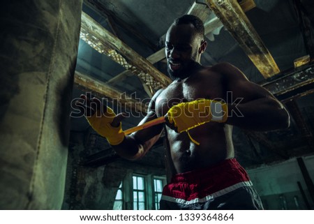 Afro American boxer is wrapping hands with yellow bandage