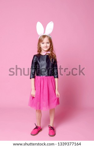 Beautiful blonde in the shape of an Easter Bunny and a blue dress with a pea pattern holds her hands at the waist. Concept of advertising and fashion. Happy Easter. Selective focus.