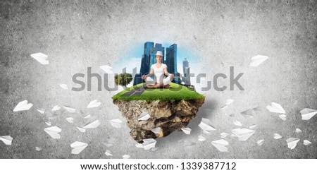 Woman in white clothing keeping eyes closed and looking concentrated while meditating on island in the air among flying paper planes with gray wall on background. 3D rendering.