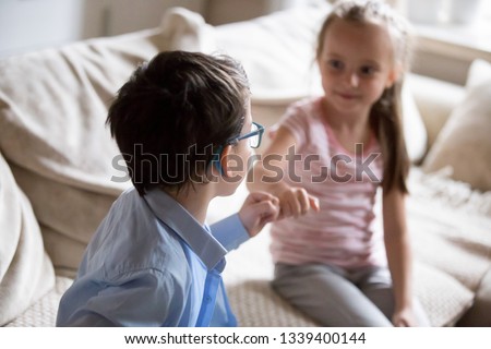 Brother and sister squeeze little fingers as sign of reconciliation. Boy and girl put up after having fight, conflict, quarrel at home Siblings relationship, kids interaction, family lifestyle concept