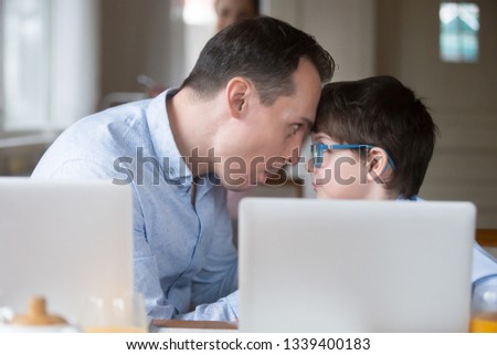 Father and son interacting having fun when playing computers. Happy family lifestyle, family relationships concept. Leisure time at home, spending weekend together. Addiction to computers, modern life