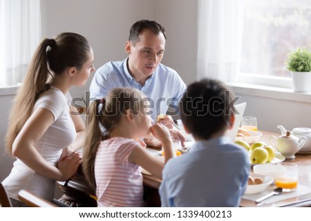 Parents watching computer while children eating breakfast at kitchen. Mother and father working having meals at dining room. Bad habit, behavior, example for kids. people addicted to gadgets concept