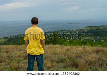 The young man looks at the village which is under the mountain. Dreaming of becoming a super hero.