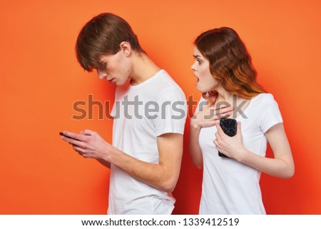 Man and woman with phones in their hands communicate on an orange background emotions