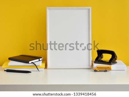 Student work place with black and yellow office supplies, books, school bus toy, empty white frame mock up.