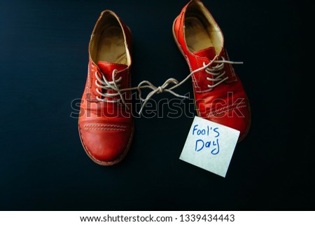 Shoes with laces tied together on black background. Shoes covered in sticky notes. April fool's day concept.