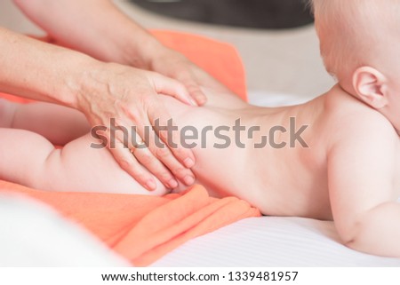 Doctor pediatric terapist a back and lumbar phisical massage to the newborn child for proper body shaping and body development. Baby back massage Royalty-Free Stock Photo #1339481957