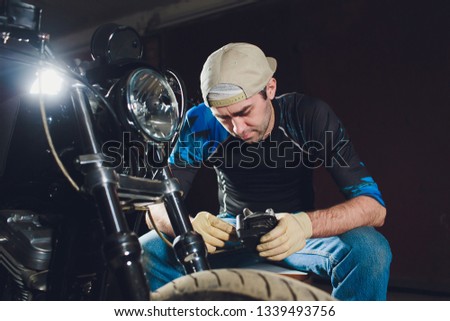 Man fixing bike. Confident young man repairing motorcycle near his garage. caliper, brake pad replacement