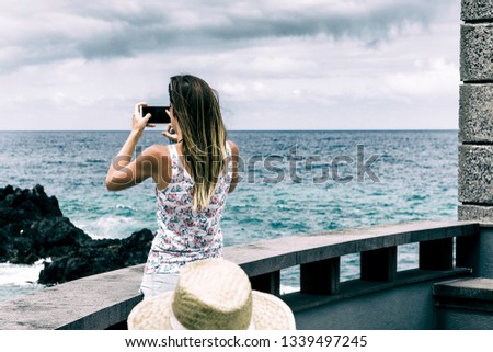 Ocean landscape.  A young woman takes pictures on the phone ocean. The woman is depicted behind. Selective focus. Copy space.