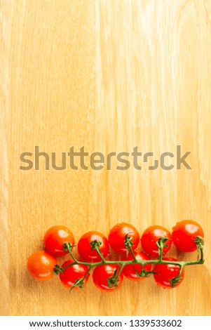 Top view photo of the cherry tomatoes branch lying isolated on the wooden table surface