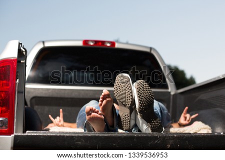 Young couple relaxing by laying down in the back of a pick up truck.  Royalty-Free Stock Photo #1339536953