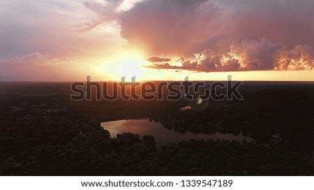 Beautiful HDR Aerial View of Sunset over Rural or suburban landscape featuring warm colors, green trees and lake reflection