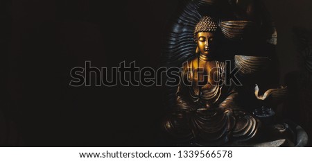 Golden Gautama Buddha statue with a black background depicting darkness and hope.