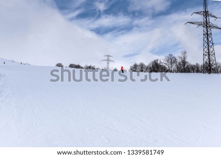 skiers and snowboarders on ski slope on sunny day