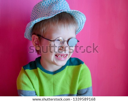 Portrait of funny child in new glasses with patch for correcting squint on pink background. boy with lost baby teeth.
Ortopad Boys Eye Patches nozzle for glasses for treatment of strabismus (lazy eye)