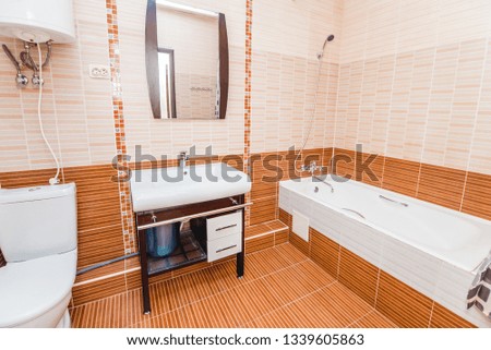 Bright picture of a bathroom with white clean bathroom with ceramic tiles with toilet sink washing machine and shower
