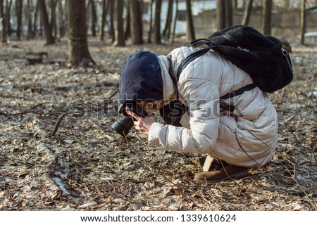 A woman with a camera is taking pictures in the autumn forest.