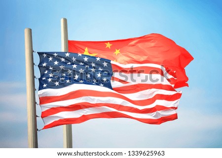 Flags of the USA and China against the background of the blue sky