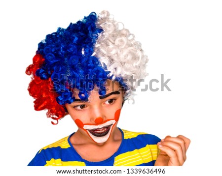 little cute smiling boy in a colorful wig with facepaint like clown looks away, pantomimic, emotions. April Fool's Day, April 1.Isolated on white.