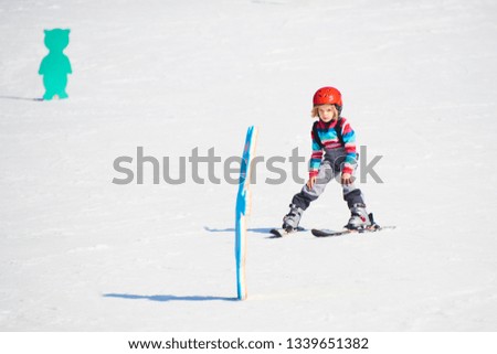 Child skiing in mountains. Active kid with safety helmet and goggles. Ski race for young children. Kids ski lesson in alpine school. Little skier racing in snow