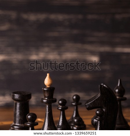 Chess pieces on a wooden chessboard against a dark background.