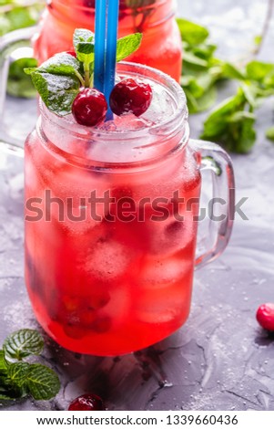 Iced homemade lemonade with cranberries, citrus and fresh mint leaf in cocktail jar with straws