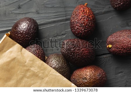 Paper bag with fresh avocado in the box on wooden dark background top view