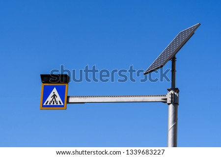 Sign of crossing of pedestrians with lights activated by a solar panel display in Bucharest, Romania, on clear blue sky
