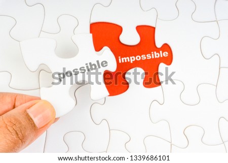 Hand holding piece of jigsaw puzzle with word POSSIBLE IMPOSSIBLE. Selective focus