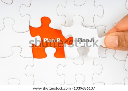 Hand holding piece of jigsaw puzzle with word PLAN A & PLAN B. Selective focus